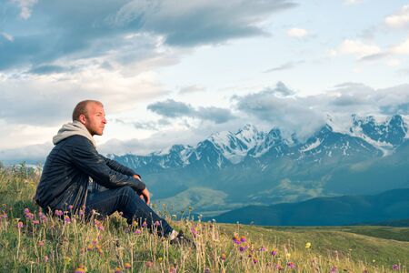 Traveler sitting on top of a mountain and looks into the distance. Mountains