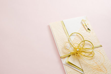 Wedding invitation or greeting card with gold ribbon on pink background.の写真素材