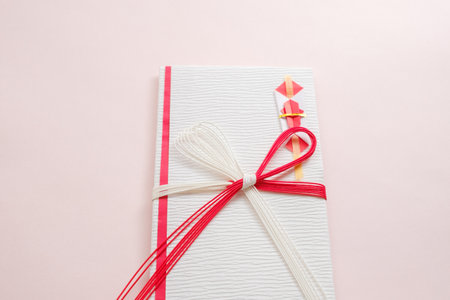 Gift with red ribbon and bow on pastel pink background