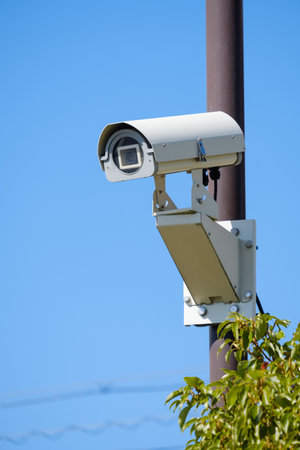 CCTV security camera on blue sky background, closeup of photo