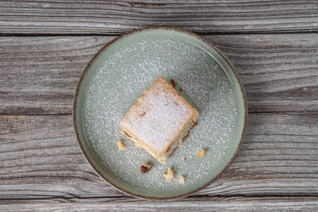 snack with delicious pie with sweet cottage cheese and raisins on a light green ceramic plate on a wooden backgroundの写真素材