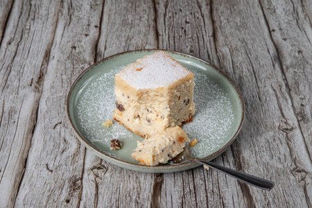 snack with delicious pie with sweet cottage cheese and raisins on a light green ceramic plate on a wooden backgroundの写真素材