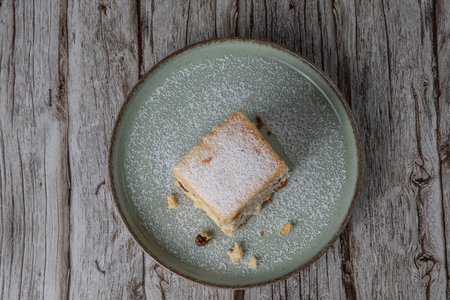 snack with delicious pie with sweet cottage cheese and raisins on a light green ceramic plate on a wooden backgroundの写真素材