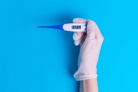 The thermometer in the hand in a rubber glove examining the body temperature of a sick person...