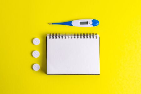 Hands with a notebook in rubber gloves with a thermometer on a yellow backgroundの写真素材