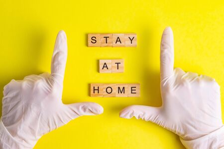 Stay at home hands in rubber gloves quarantine self-isolation on a yellow backgroundの写真素材