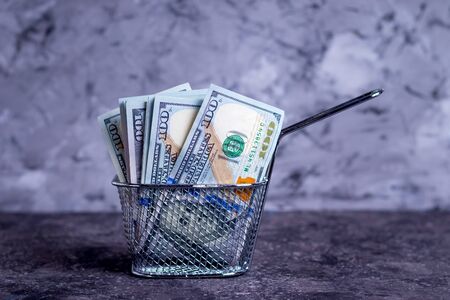 Money bank notes in a deep fat sieve for opening a small business fast food on a gray backgroundの写真素材