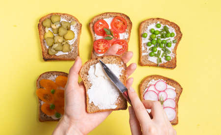 Breakfast sandwiches with vegetable vegetarian fillings woman spreads cream cheese toast