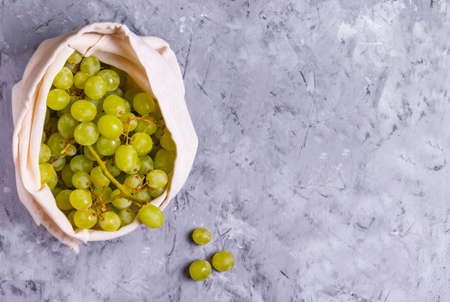Grapes in a reusable eco cotton bag on a gray backgroundの写真素材
