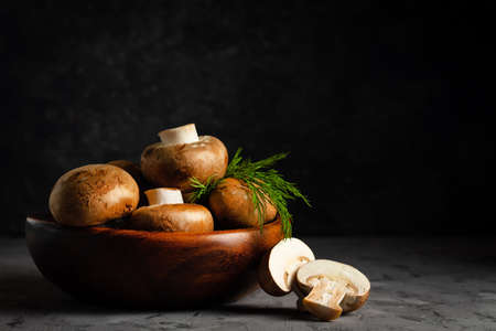 Brown champignons with dill in a wooden plate in a low keyの写真素材