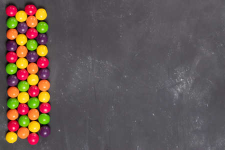 Multi-colored round candies in a row on a gray board copy spaceの写真素材
