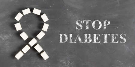 The inscription Stop diabetes in chalk on a gray board with a lump sugar ribbon for World Diabetes Day November 4の写真素材