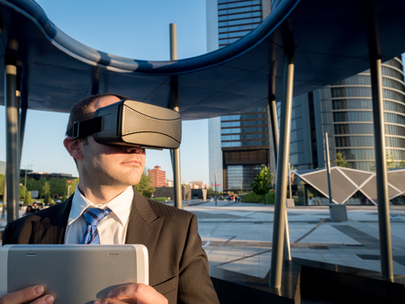 Businessman using virtual reality glasses with a tablet in a business center. New technologies and future business concept.の写真素材