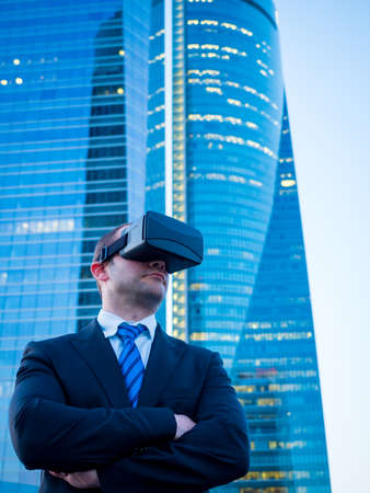 Confident businessman using virtual reality glasses in a business center. Leadership in new technologies and future business concept.の写真素材