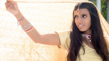Beautiful and young traditional hindu woman holding a backlit veilの写真素材