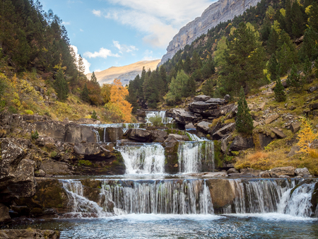 Background of a colorful valley in autumn with a waterfallの写真素材