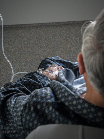 Old patient man with iv drip in the hand in the hospital