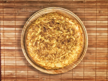 Spanish tortilla on wooden plate. The tortilla is a typical dish in Spain that is prepared with olive oil, eggs and potatoes.の写真素材