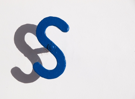 metal object shaped S and isolated on a wall background の写真素材