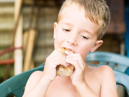 Little boy eating a sandwich outdoors  in a summer dayの写真素材