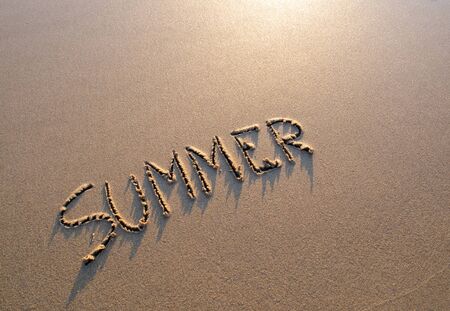 Word summer written in the sand. The text is written in the sand of a beach.の写真素材