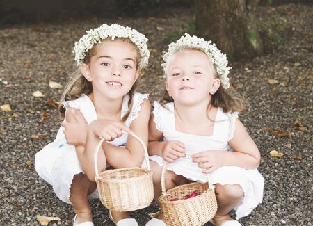 Two little girls dressed for a wedding. The girls are bowed, smiling and looking at camera.の写真素材