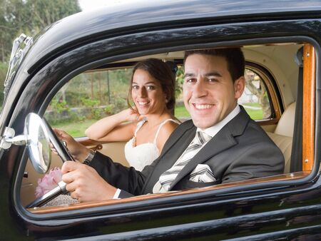 Married couple in a old car. They are looking at camera.の写真素材