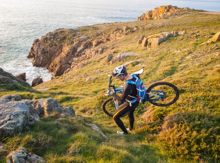 Cyclist carrying your bike on the Galician coast. The man is in a nice setting and practice mountain bike.の写真素材