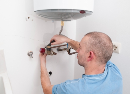 Plumber repairing an electric boiler inside homeの写真素材