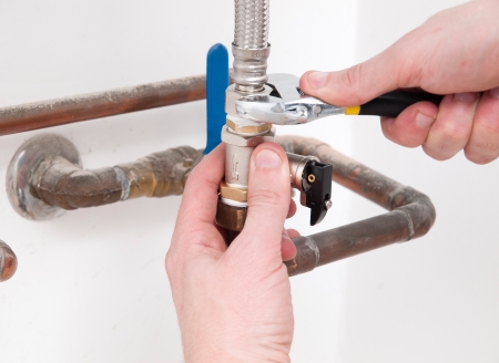 Hands repairing the plumbing pipes of an electric boiler with a spannerの写真素材