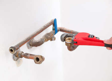 Hands repairing the plumbing pipes of an electric boiler with a stilson wrenchの写真素材