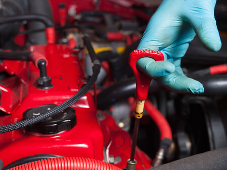 Mechanic checking the oil level in a engine car in a garage