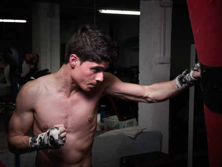 Young caucasian Boxer training with a punching bag in his home gym