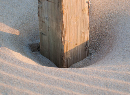 Wooden post buried in the sand on the beachの写真素材