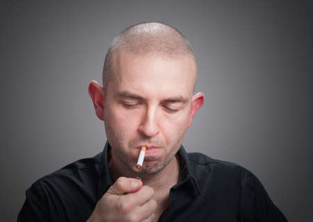 Man lighting a cigarette and isolated on dark background.の写真素材