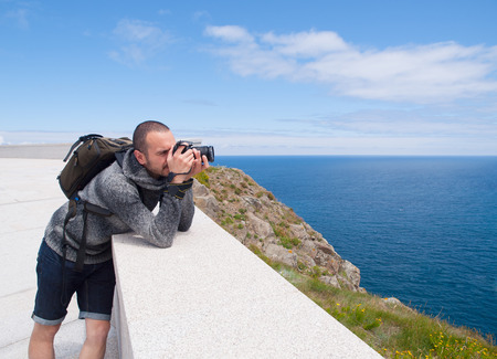 Photographer sightseeing and photographing a beautiful coastal landscape in Galicia, Spain