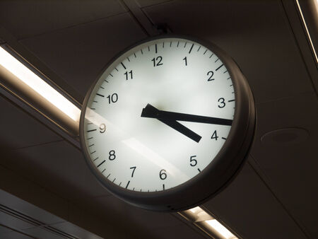 Big watch in an airport. The watch is suspended from the ceiling.