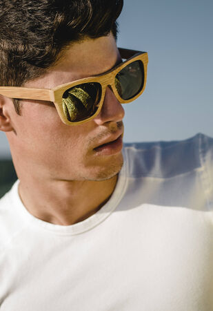 Model man portrait with wooden sunglasses outdoors in a sunny dayの写真素材