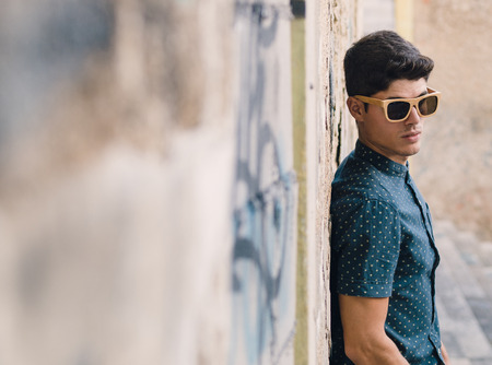 Fashionable man portrait over ruinous wall background outdoorsの写真素材