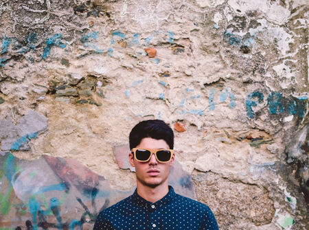 Fashionable man portrait over ruinous wall background outdoorsの写真素材