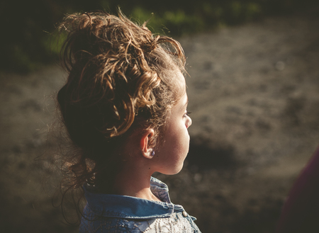 Little girl lookin aside outdoors in a sunny dayの写真素材