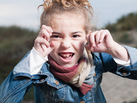 Blonde girl putting a frightening face outdoors