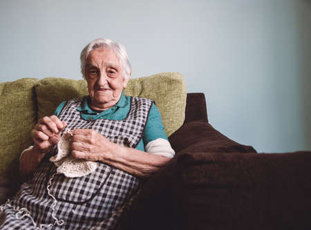 Elderly woman sewing at home.の写真素材