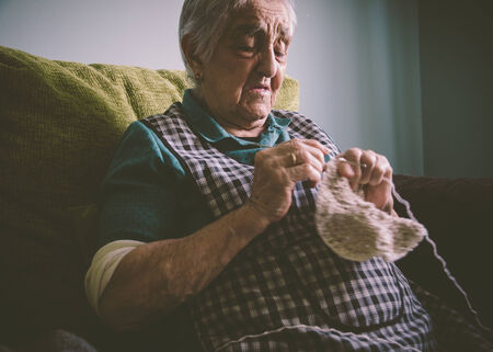 Elderly woman sewing at homeの写真素材