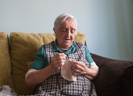 Elderly woman sewing at homeの写真素材