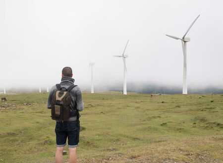 Man contemplating wind turbines in nature on a foggy day