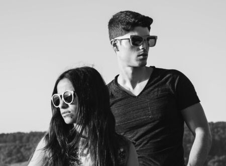 Model couple in a portrait outdoors. Couple is using sunglasses.