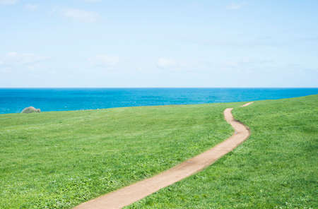 Field, path, sea and sky in horizontal composition.の写真素材