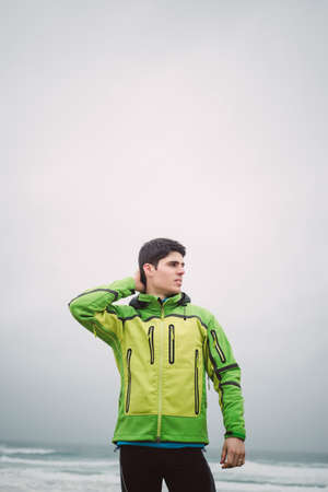 Portrait of a runner man on the beach in a cloudy day with copy space avobe.