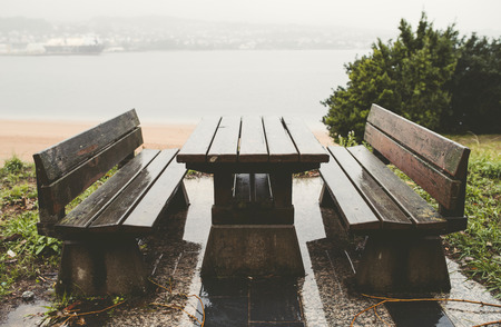 Picnic table and benches in a park on a rainy summer dayの写真素材